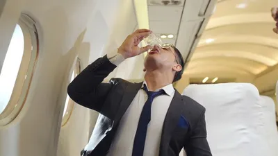 Бизнесмен пьет воду в самолете | Премиум Фото